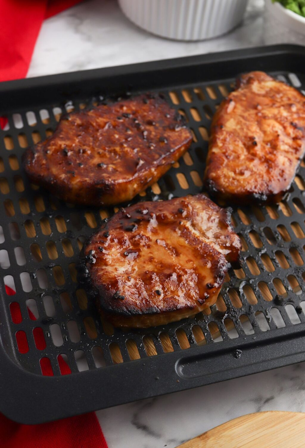 Three grilled pork chops on a grill rack.