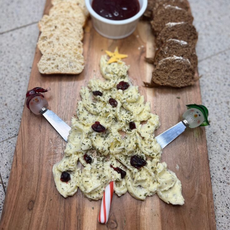 A Christmas tree shaped cheese board adorned with bread and cranberries.