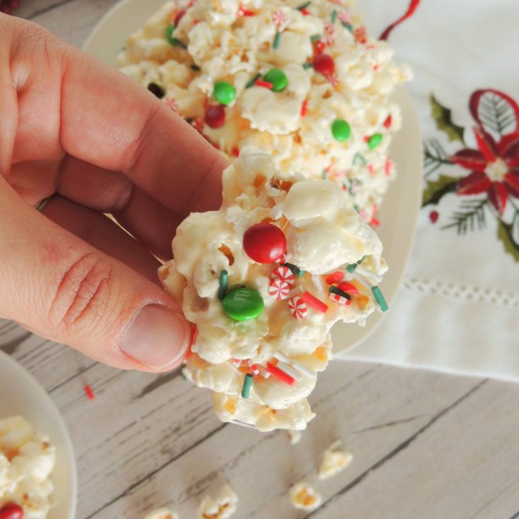 A hand holding a piece of christmas popcorn.