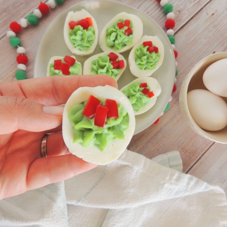 Deviled eggs with holly leaves on a plate.