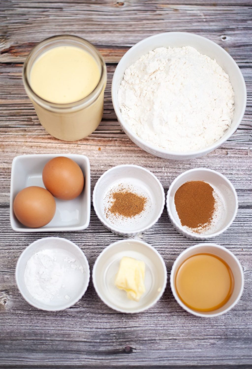 Ingredients for a cake including flour, eggs and butter on a wooden table.