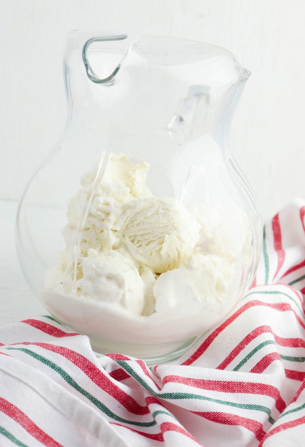 Ice cream in a glass pitcher on a white table.