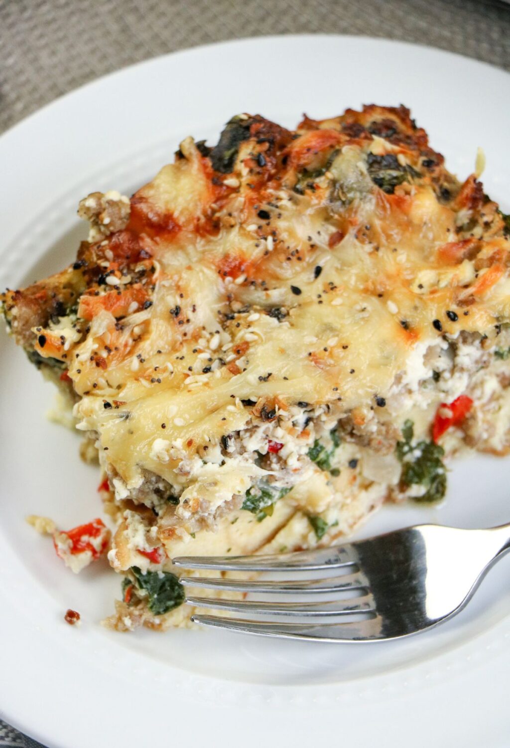 A slice of breakfast casserole on a plate with a fork.