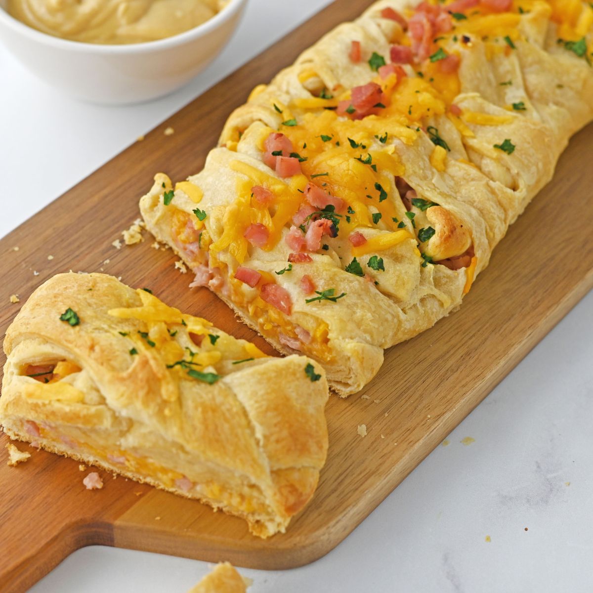 A ham and cheese crescent roll on a cutting board.