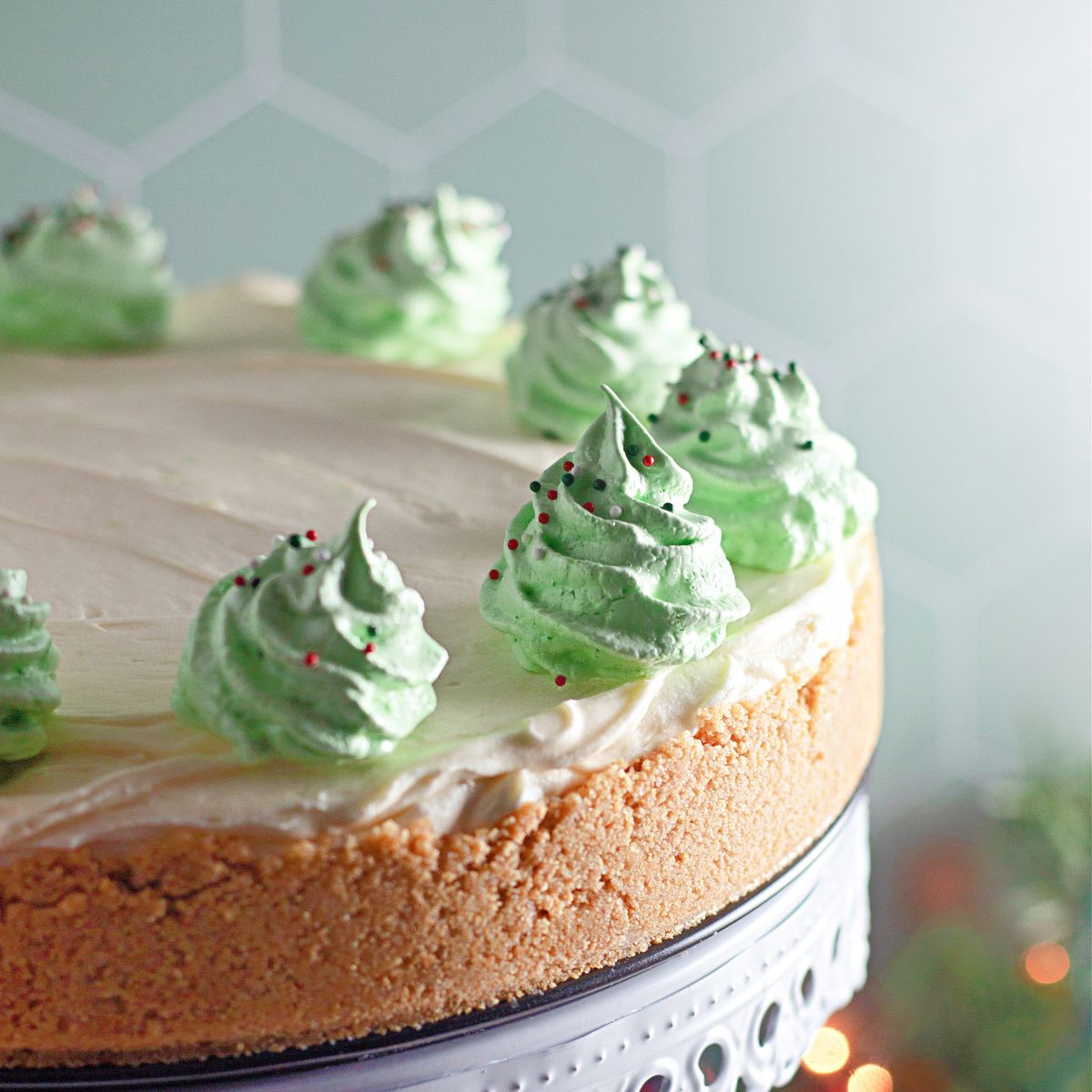A green frosted cake on a cake stand.
