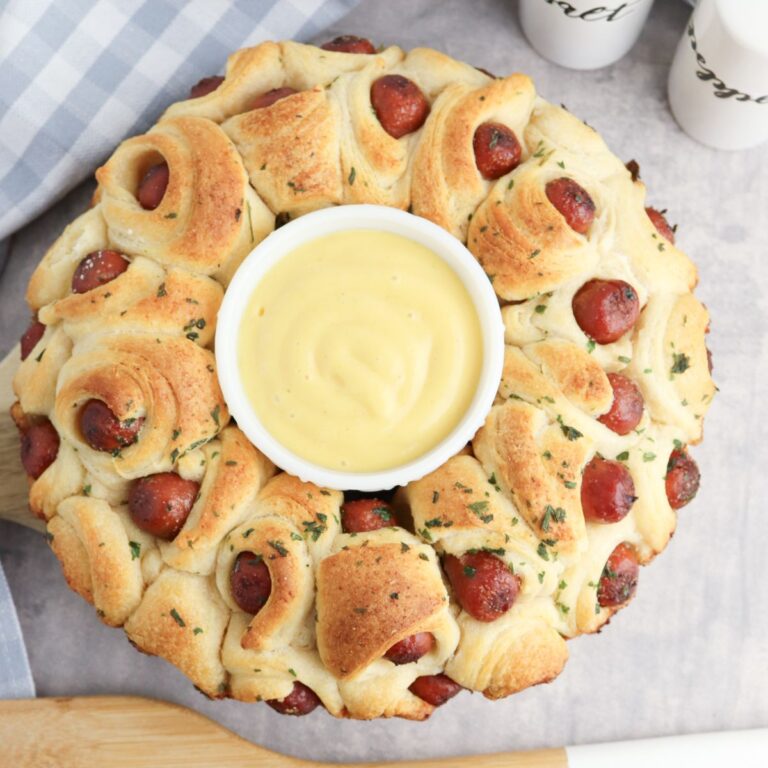 A bundt cake with hot dogs and dipping sauce.