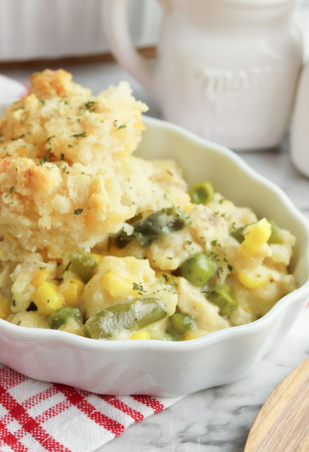A white dish with mashed potatoes, corn and peas.