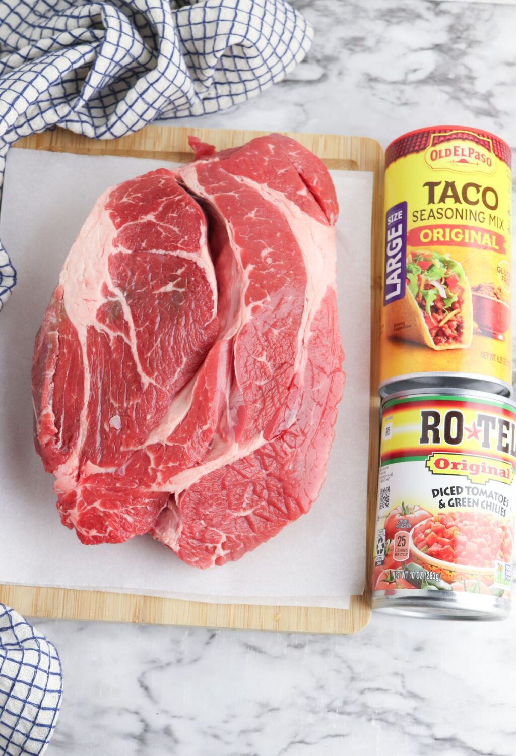 A cutting board with meat, taco seasoning, and a can of taco sauce.