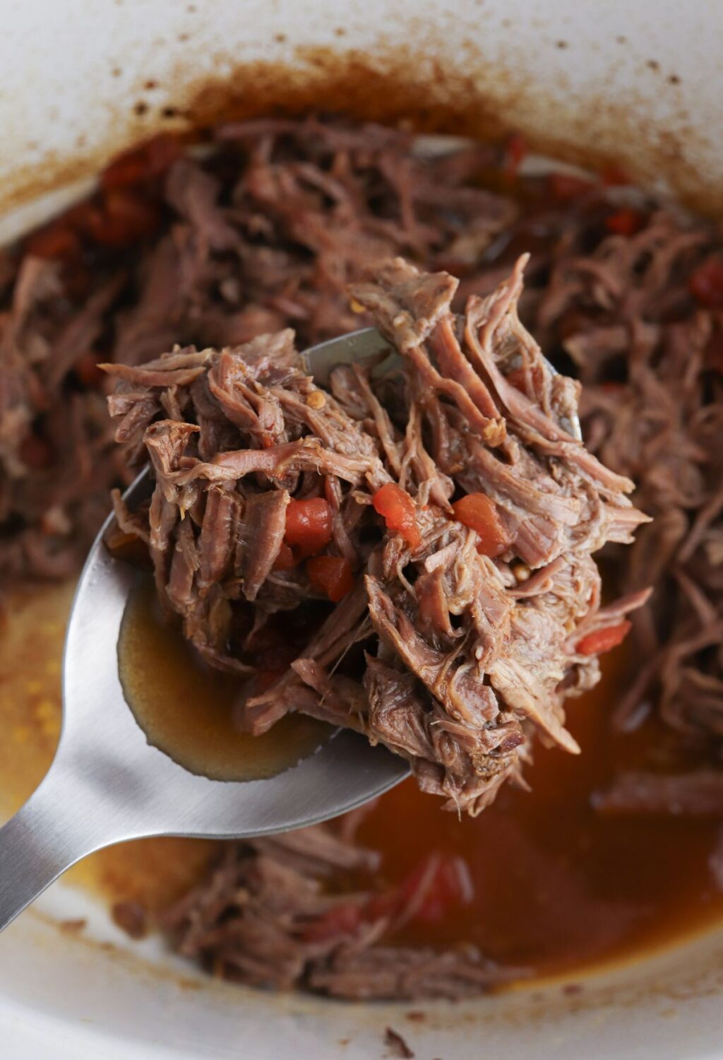 A spoonful of beef in a slow cooker.