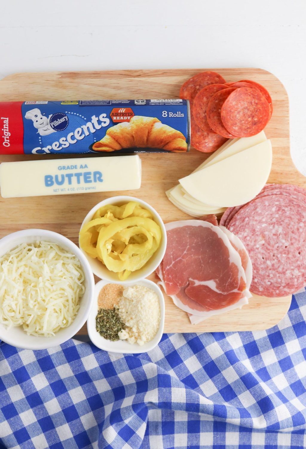 A cutting board with meat, cheese, bread and butter.