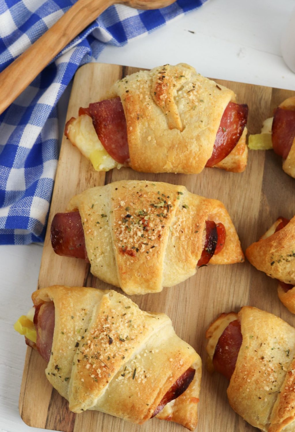 Ham and cheese crescent rolls on a wooden cutting board.