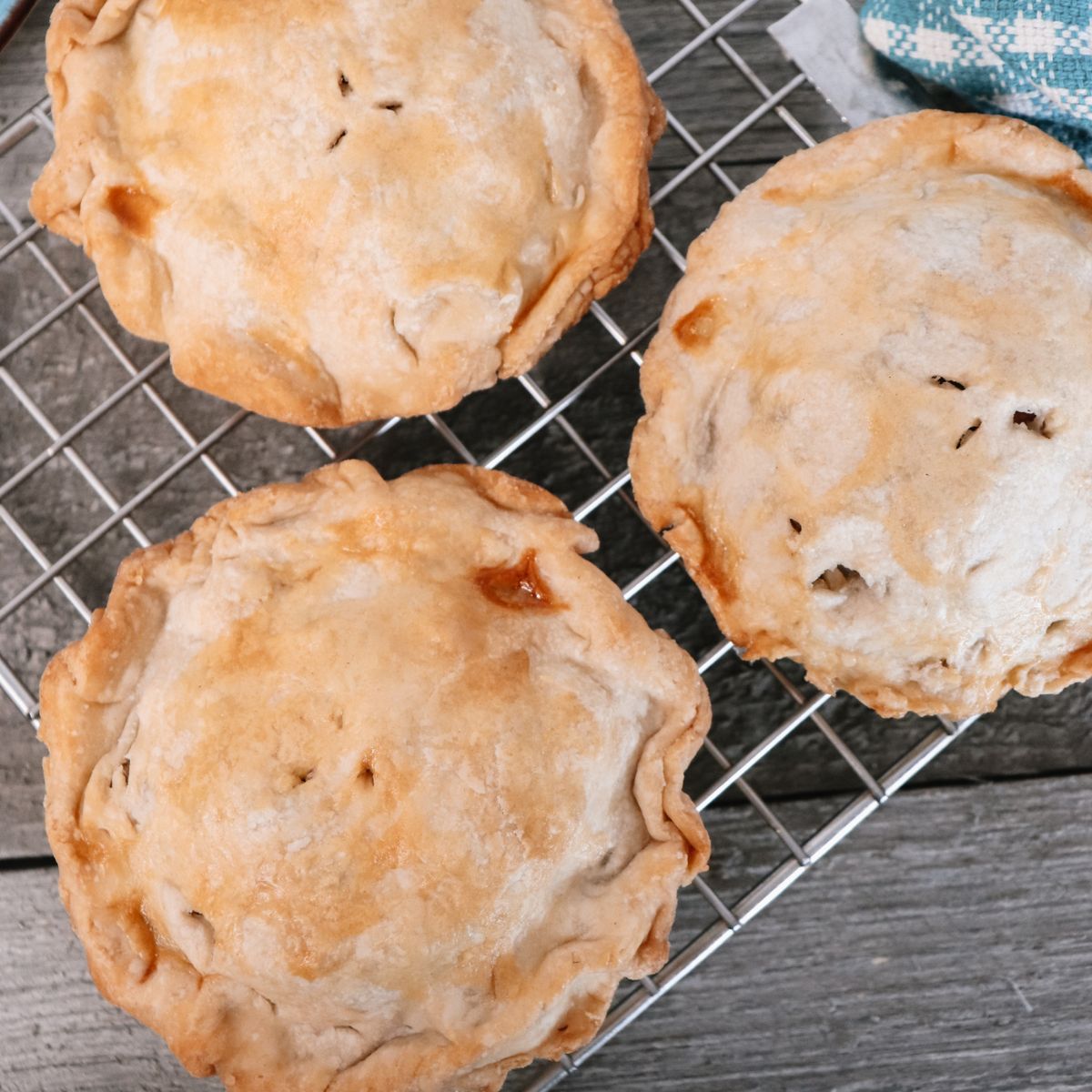 Three apple pies on a cooling rack.
