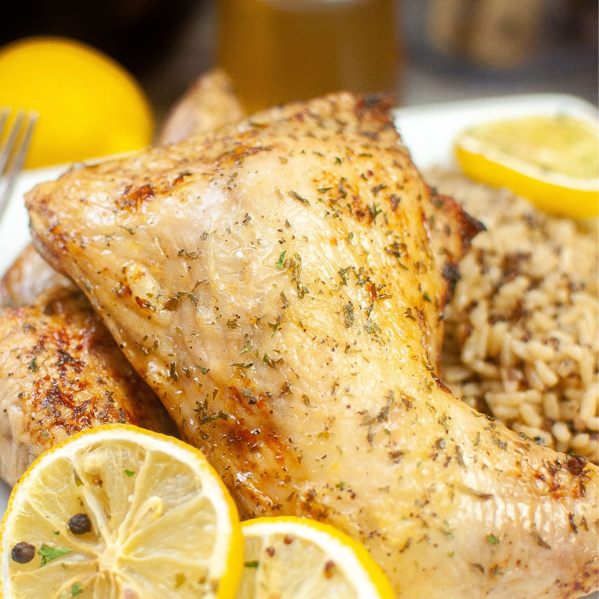 A plate with chicken, rice and lemons.