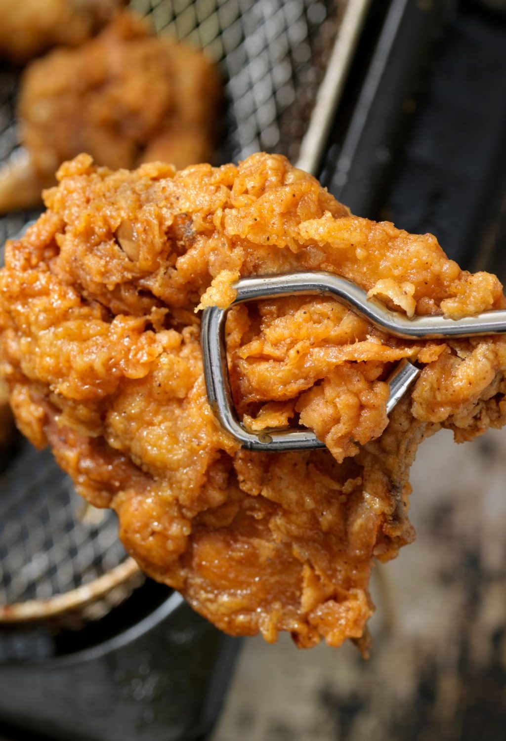 A fork is being used to pick up a piece of fried chicken.