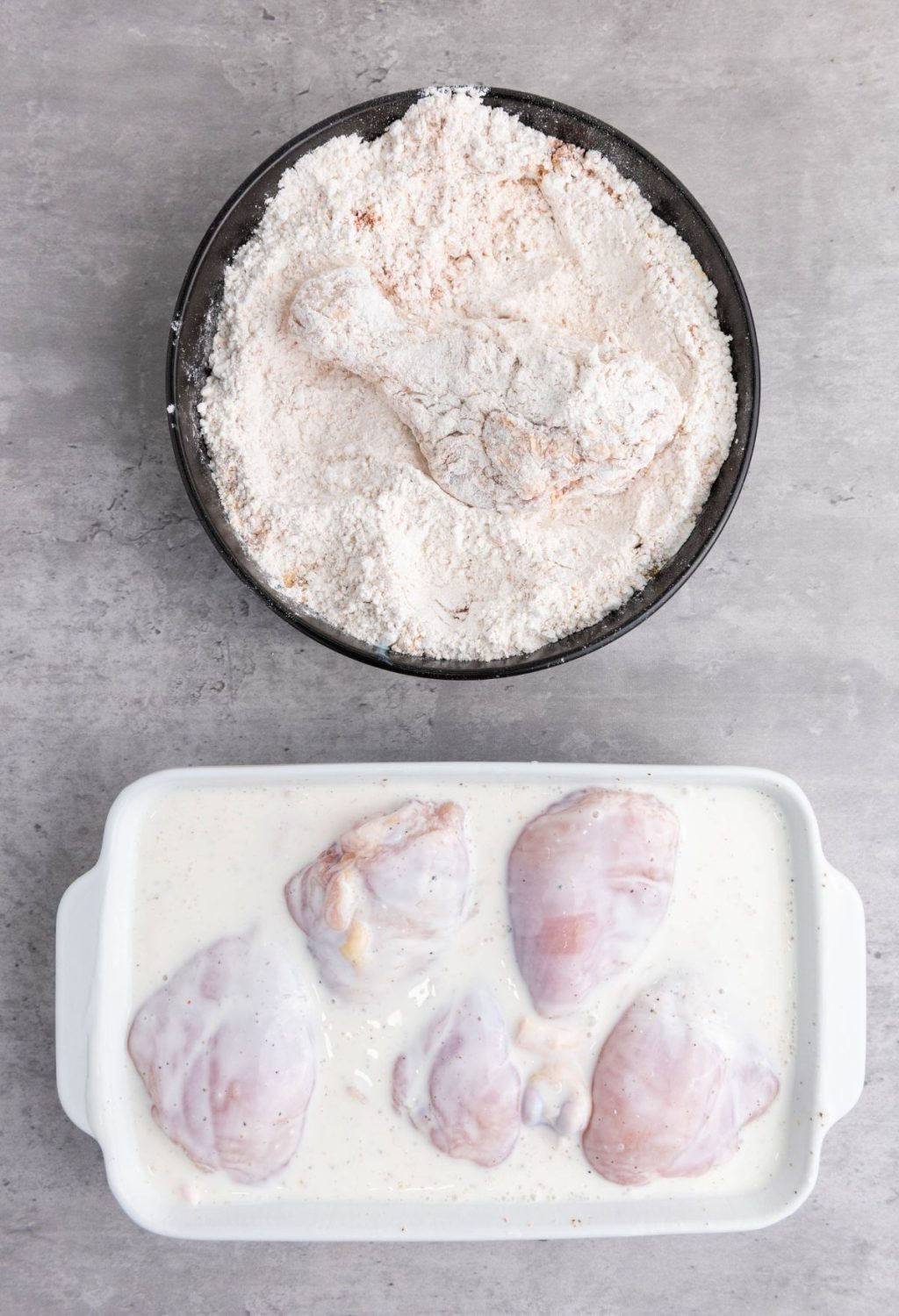 Chicken breasts in a baking dish next to a bowl of flour.