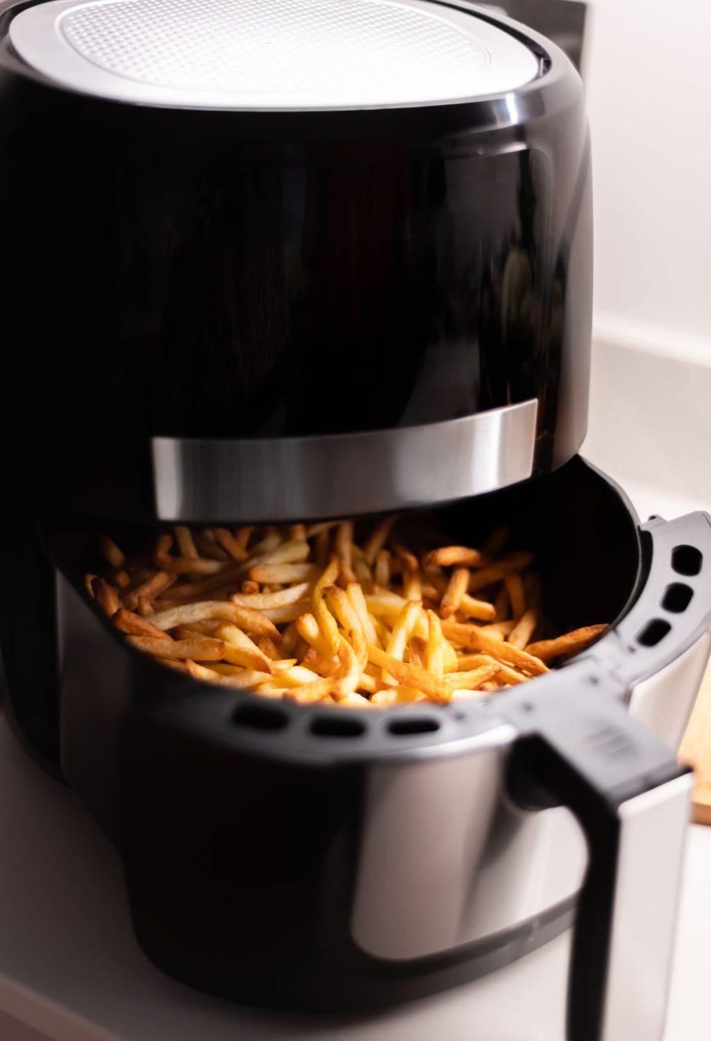 A black and silver machine with a black container full of french fries that set off the smoke alarm due to its air fryer setting.