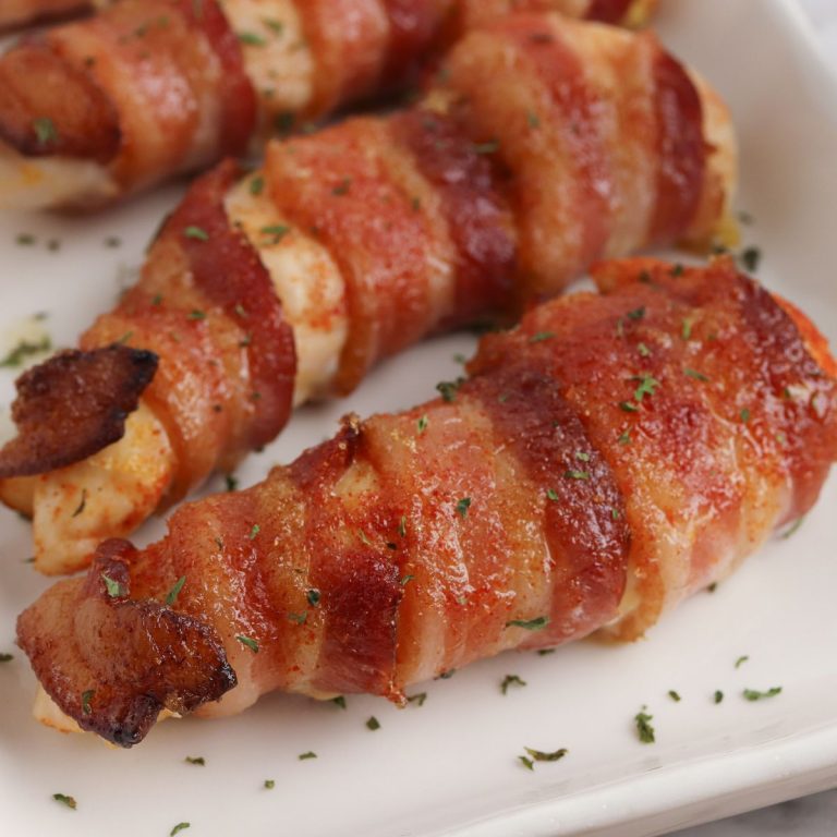 Bacon wrapped chicken breasts on a white plate.