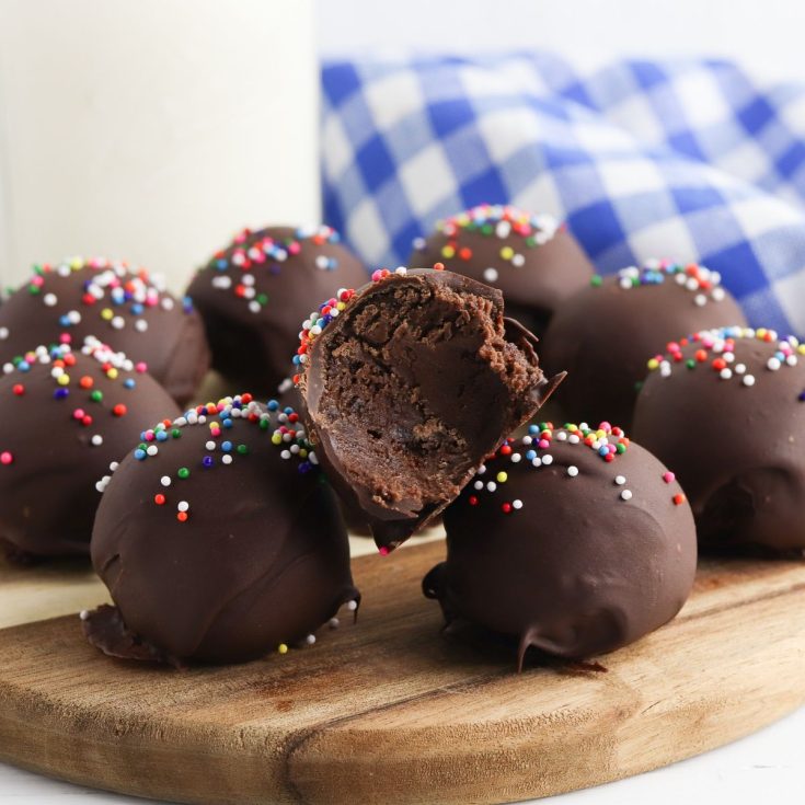 Chocolate truffles with sprinkles on a cutting board.