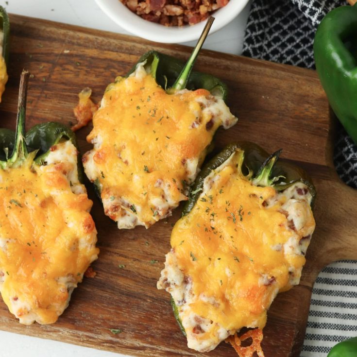 Stuffed peppers with cheese on a cutting board.