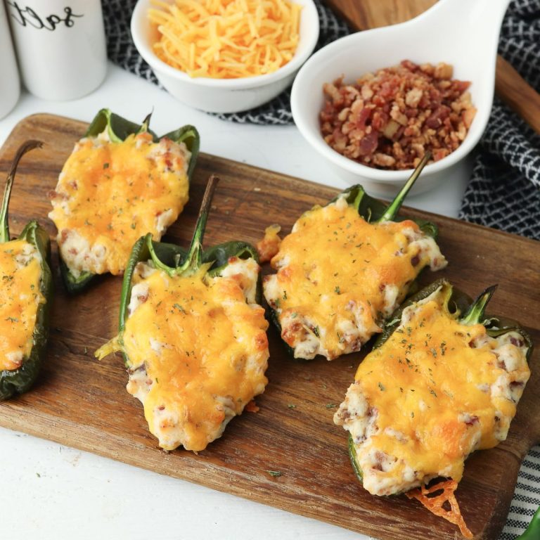 Stuffed jalapenos on a wooden cutting board.