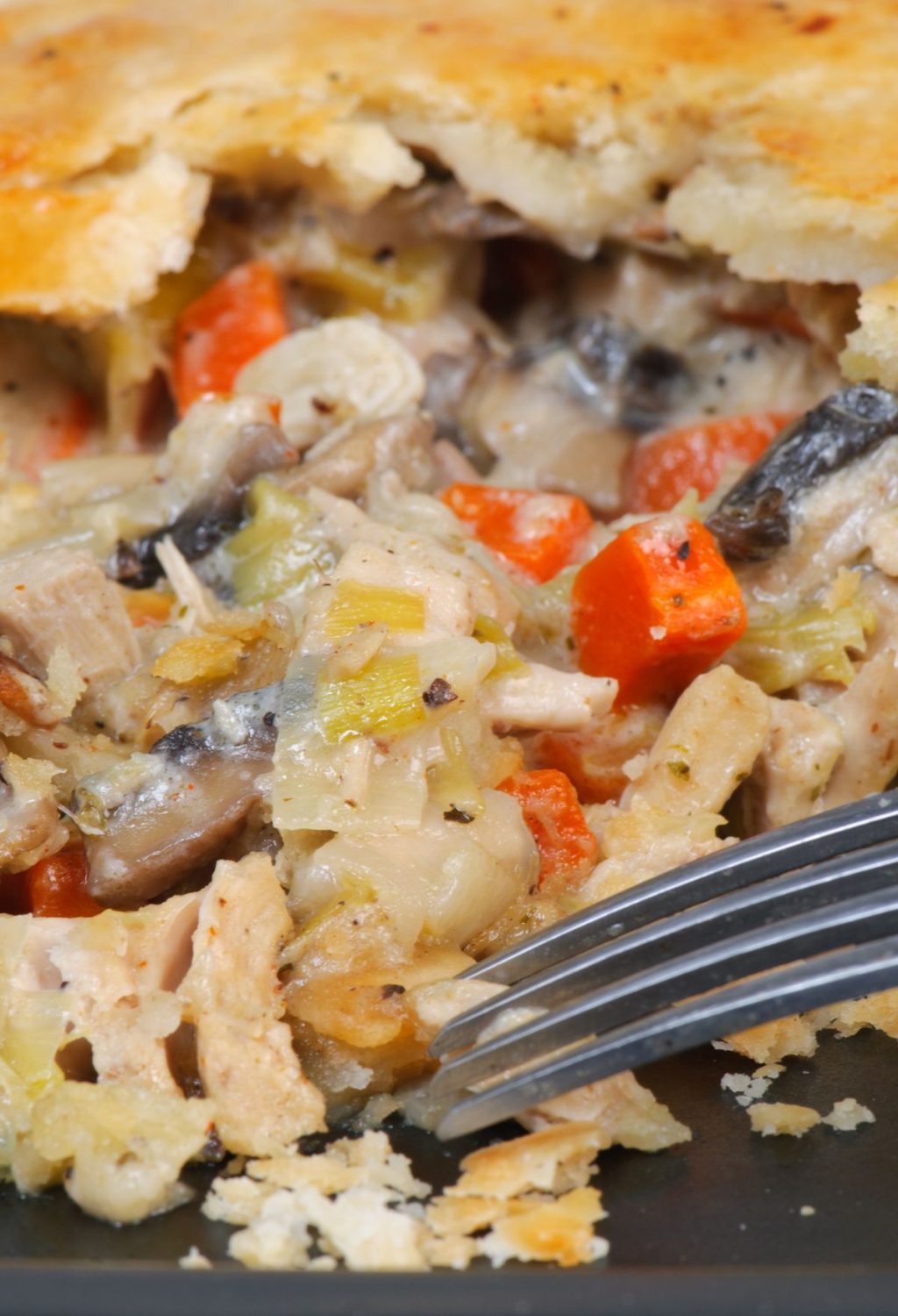A chicken pot pie with vegetables and a fork.
