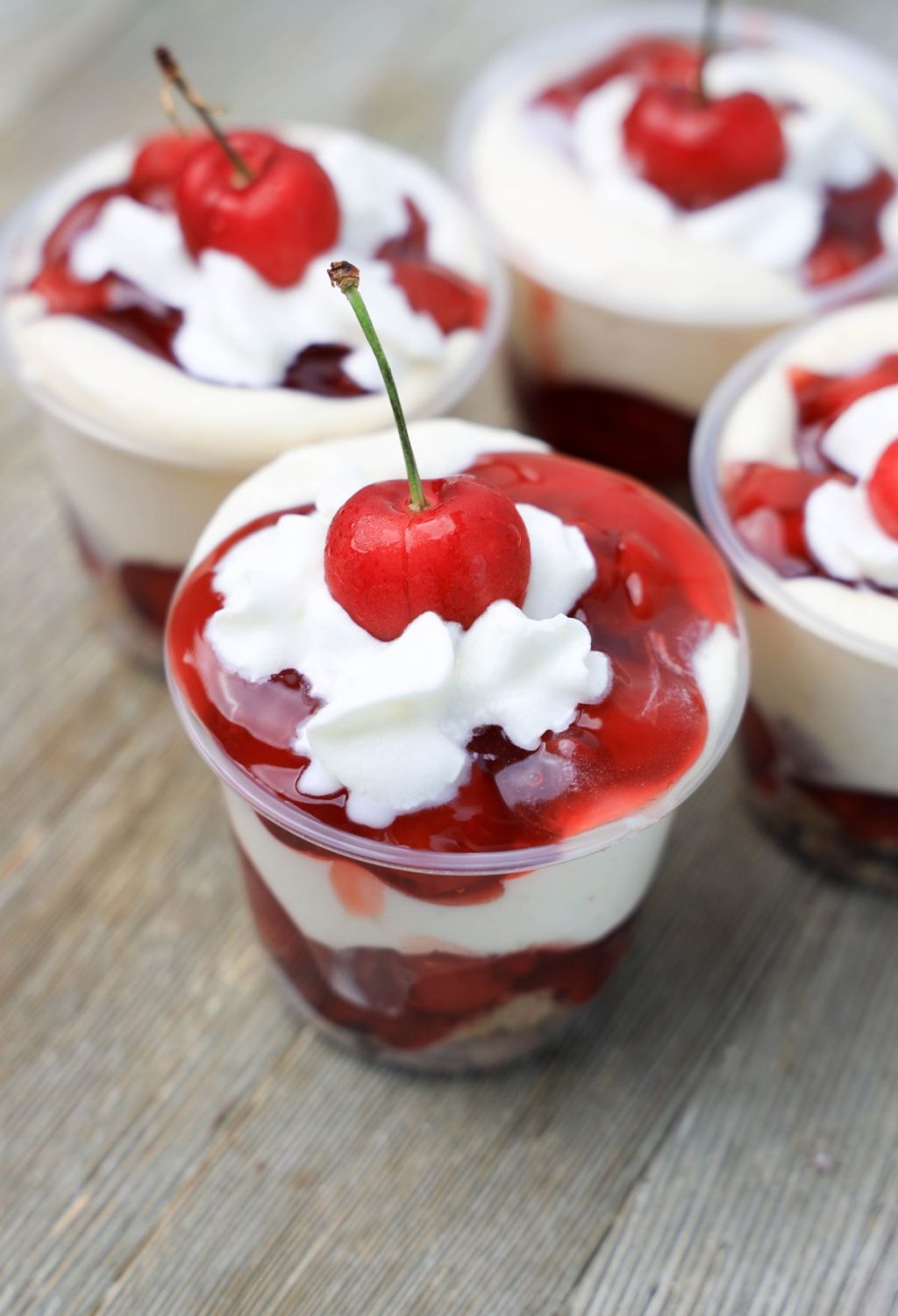 Cherry cheesecake cups with whipped cream and cherries.