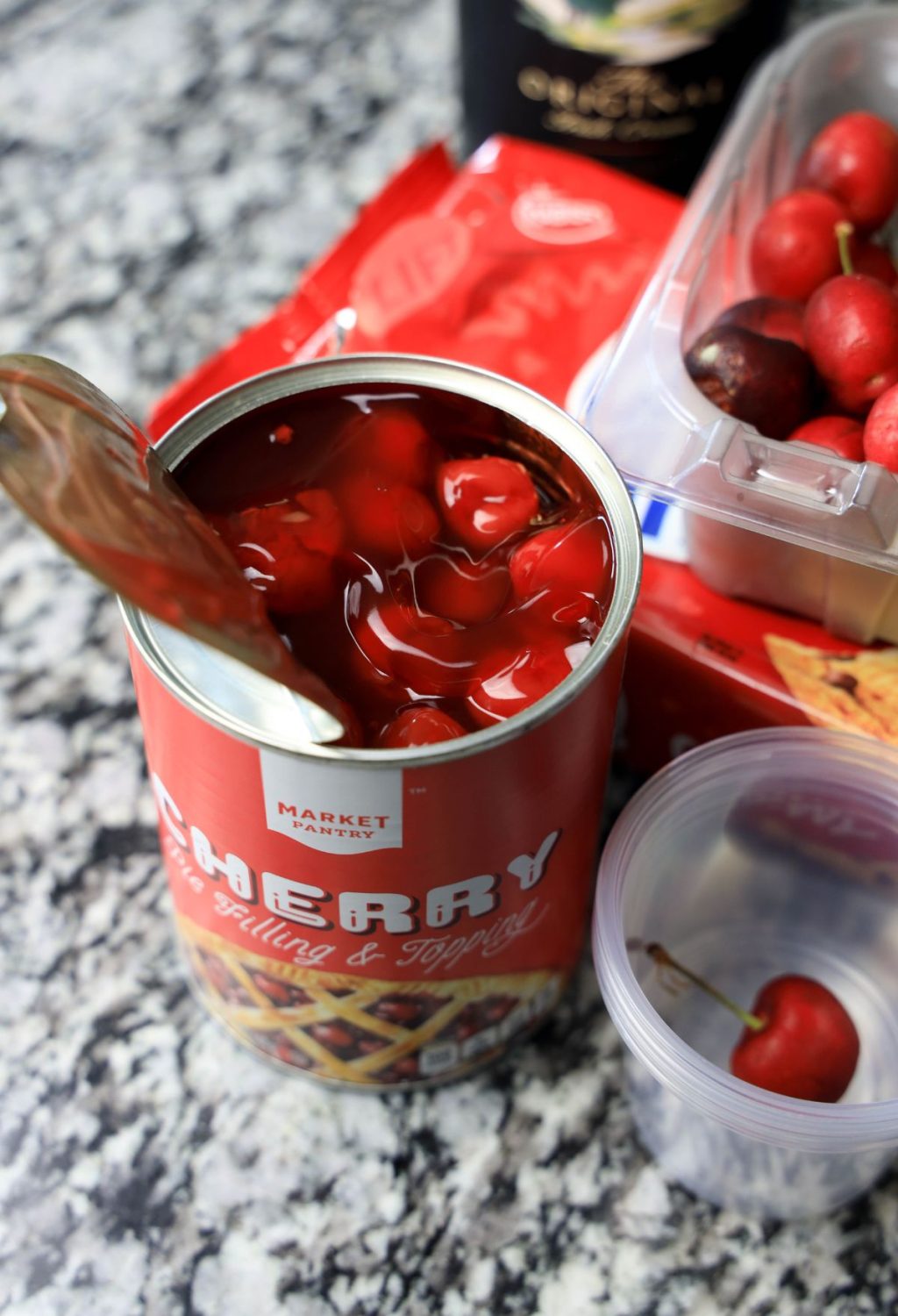 A can of cherry sauce on a counter next to a bottle of wine.