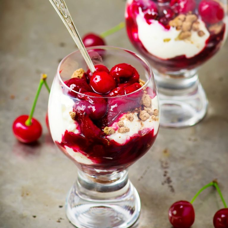 Two glasses filled with cherry ice cream and granola.
