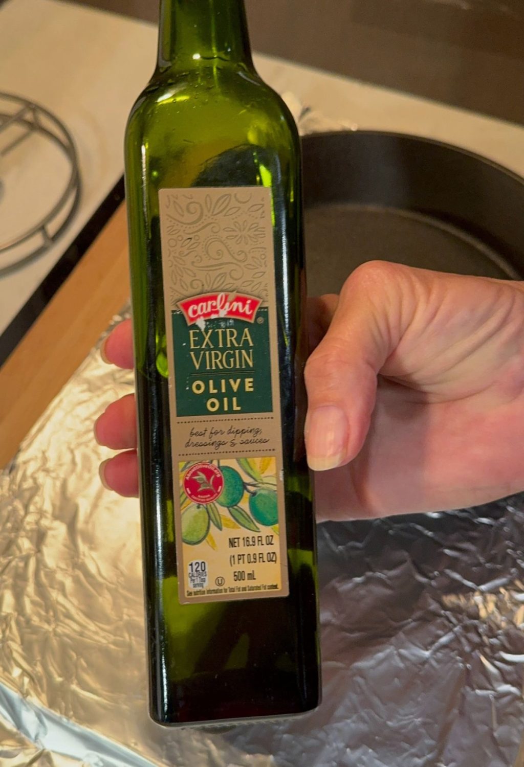 A person holding a bottle of olive oil.