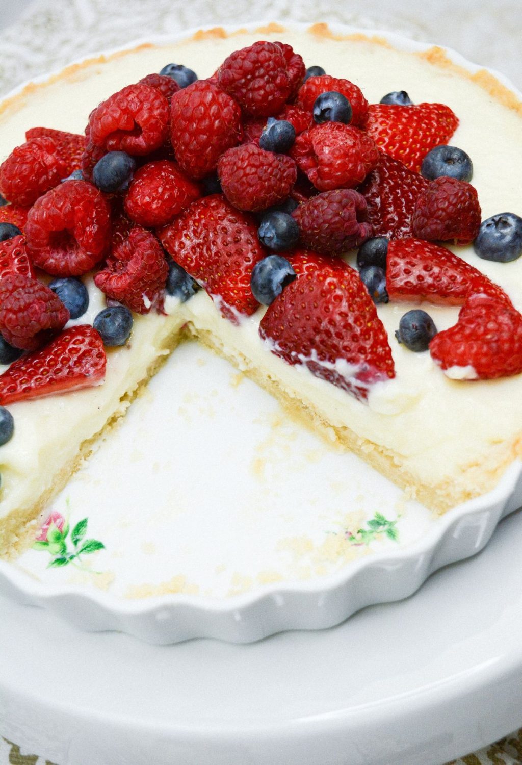 A pie with berries and cream on a white plate.