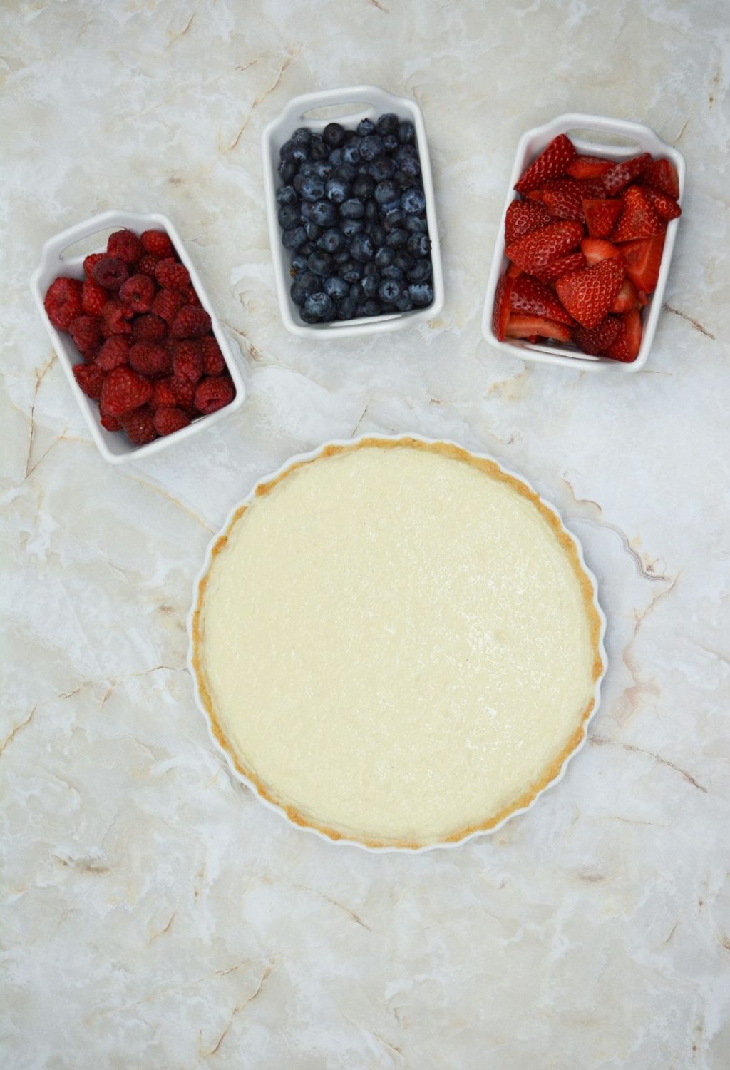 A pie with berries and cream in a white dish.