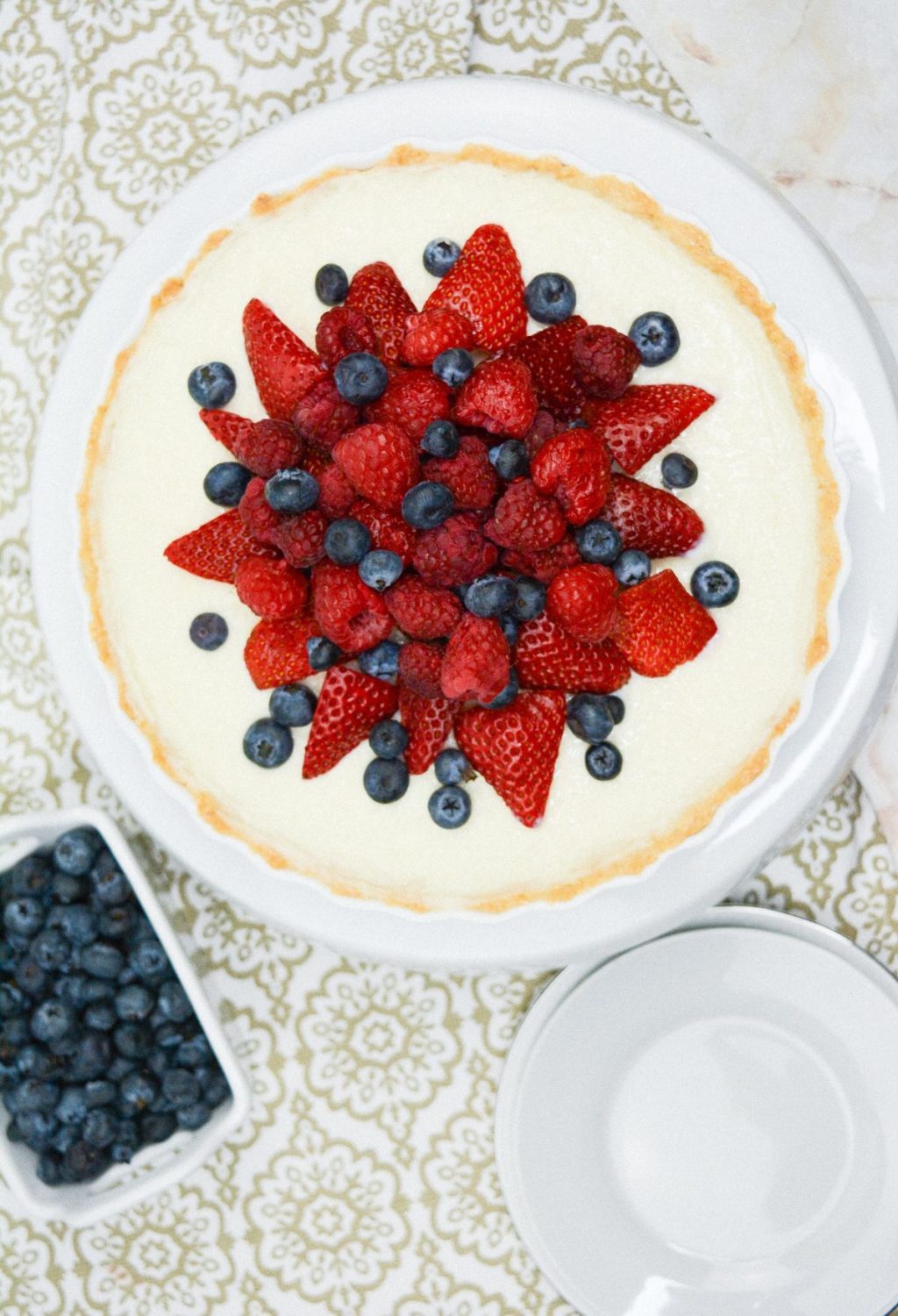 A white plate with a blueberry and strawberry tart on it.