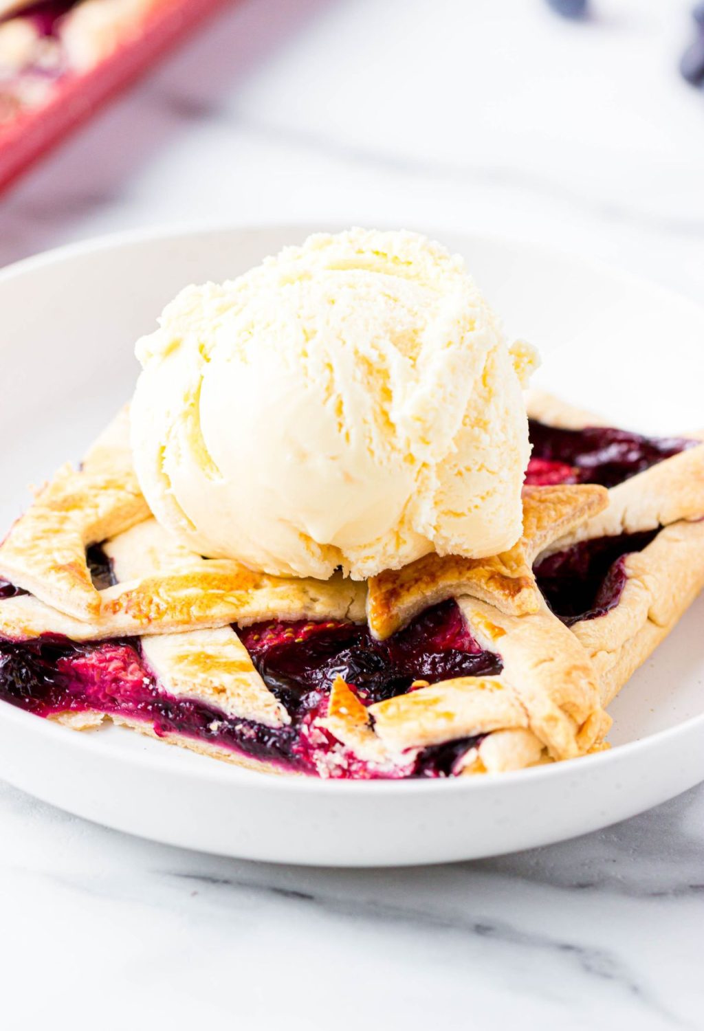 A blueberry pie with ice cream on a plate.