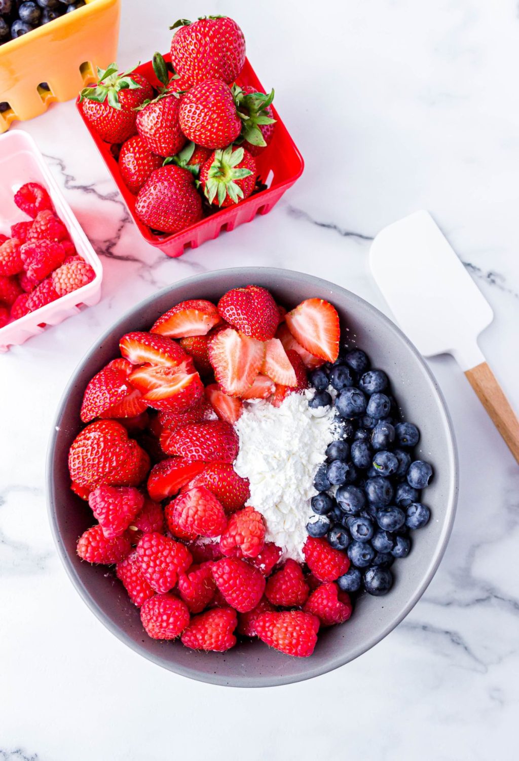 A bowl full of strawberries, blueberries and raspberries.