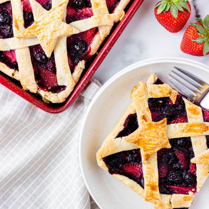 A pie with strawberries and blueberries on a plate.