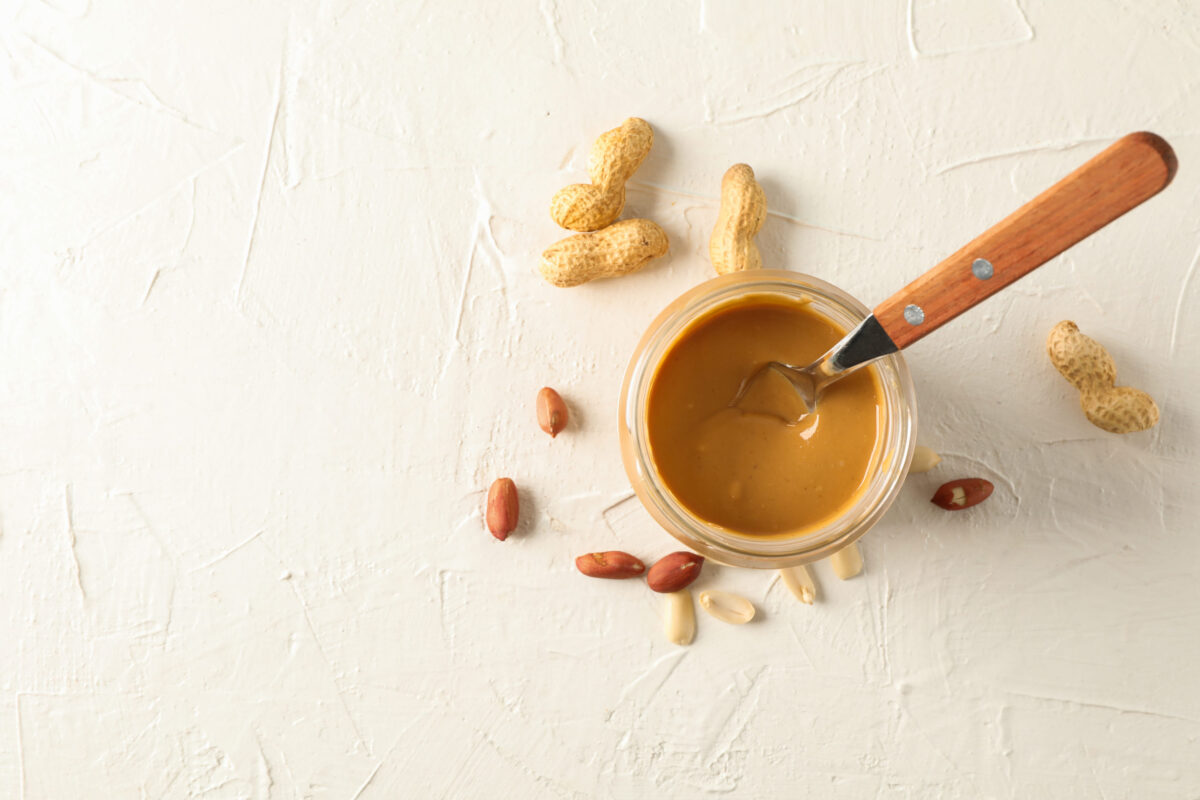The 8 Most Common Foods That Could Be Triggering Your Allergies 1 Glass jar with creamy peanut butter and spoon, and peanut on white background, space for text and top view