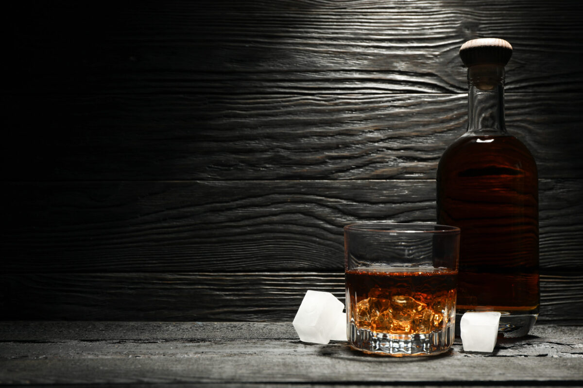 8 Whiskey Brands You Should Never Waste Your Money On 3 Bottle and glass of whiskey and ice cubes on wooden background, space for text