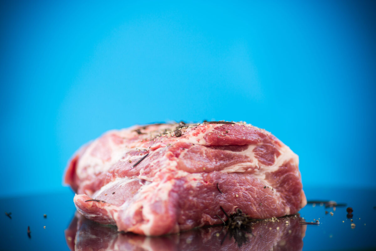 10 Toxic Foods That Are Secretly Destroying Your Gut 1 pork piece raw meat with spices and rosemary on a blue background