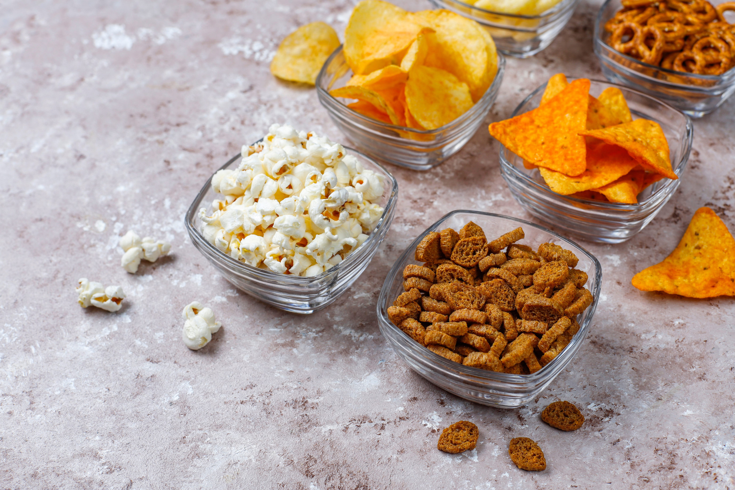 Salty snacks. Pretzels, chips, crackers,popcorn in bowls. Unhealthy products. food bad for figure, skin, heart and teeth. Assortment of fast carbohydrates food