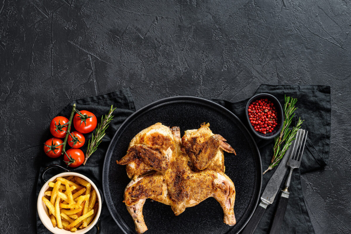 The 10 Foods You Should Never Cook on Cast Iron 4 Halves of grilled juicy chicken with golden brown crust in a pan. Black background. Top view. Space for text.