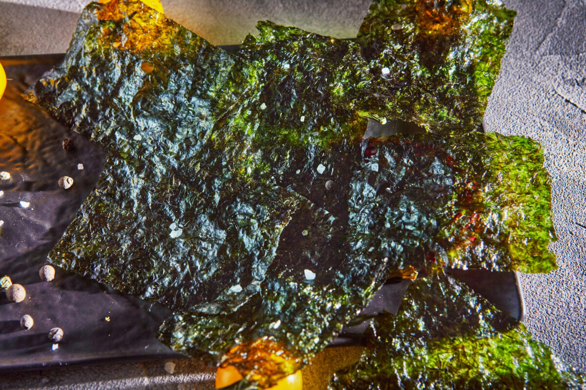 The Truth Behind Overrated Foods 2 Crispy nori seaweed with cherry tomatoes and dark spices on gray concrete. Japanese food nori. Dried sheets of seaweed. Close-up