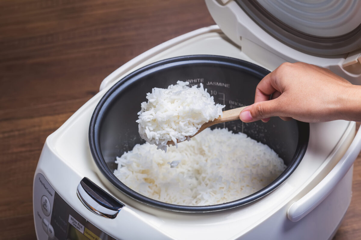 The 7 Foods You Should Never Cook in an Air Fryer 3 Woman hand is scooping jasmine rice cooking in electric rice cooker with steam. Thai Jasmine rice.