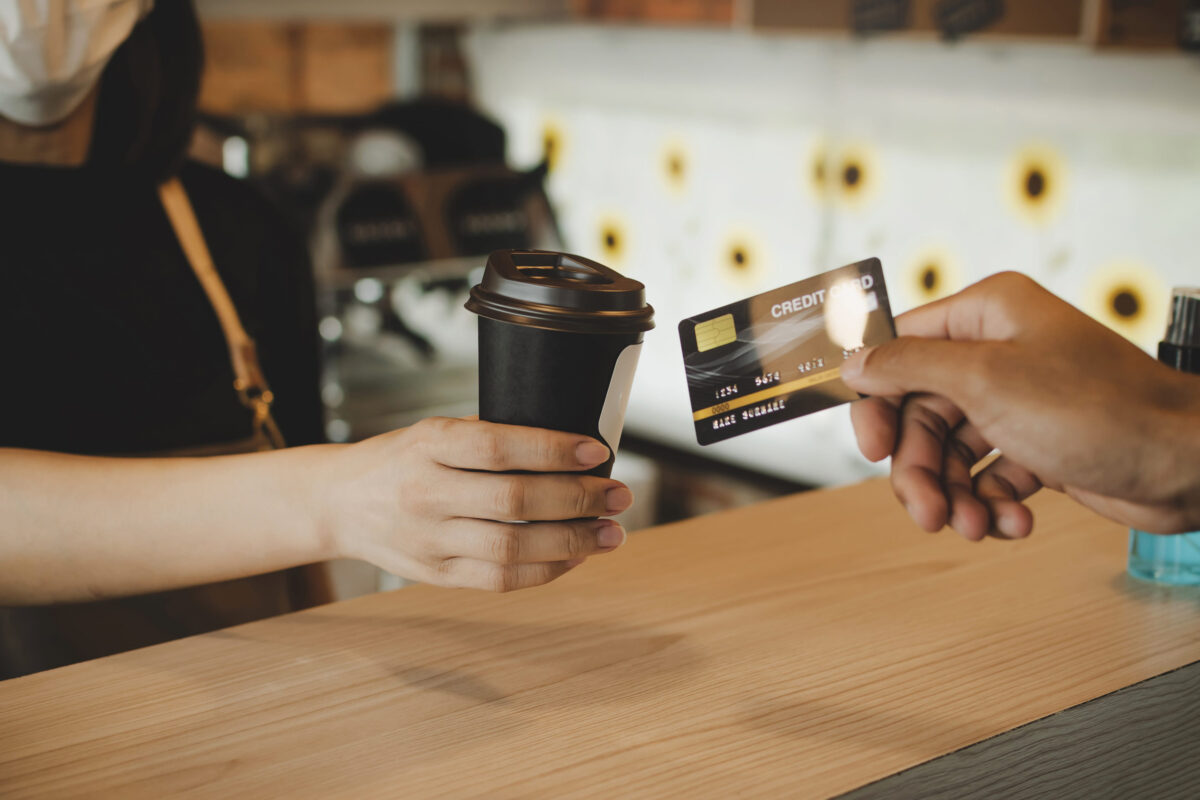 8 Recession Red Flags That Should Worry Americans Right Now 4 hand customer paying with credit card for buying hot coffee cup on counter in modern cafe coffee shop, cafe restaurant, digital payment, small business owner, takeaway food, food and drink concept