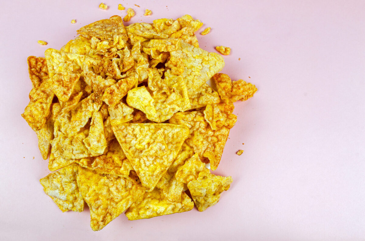 11 Discontinued Foods We Miss From the 90s 1 a bunch of corn crumbs with a tomato flavor on a pink background in the top view with space for text