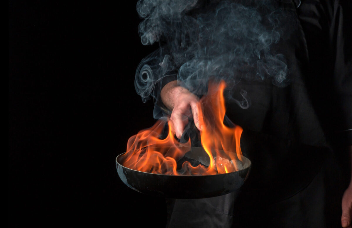 11 Common Mistakes That Are Ruining Your Fried Eggs 3 Chef cooking food in pan with fire flame on black background. Restaurant and hotel service concept. Free advertising space