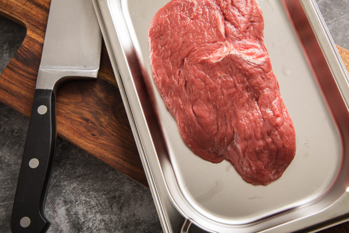 10 Popular Foods That Can Quickly Go Bad If You Store Them Incorrectly 4 Raw beef steak on stainless steel tray, wooden board and dark stone background