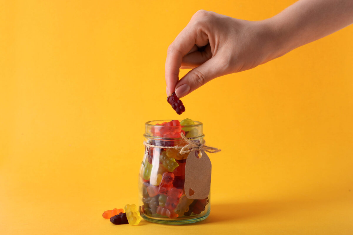 10 Foods That Are Ruining Your Movie Night, and Why You Should Avoid Them 2 Woman taking gummy bear candy from glass jar on yellow background, closeup