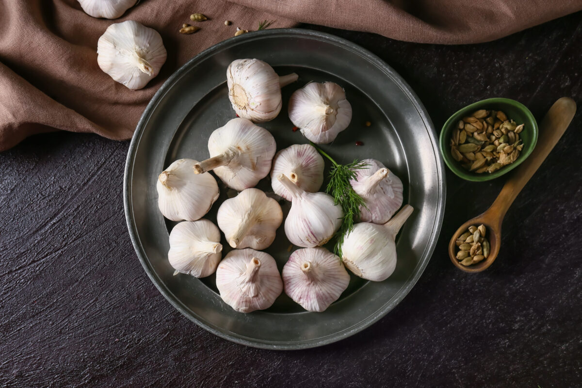 Foods You Should Never Cook in Aluminum Foil 3 Plate with fresh garlic on dark table