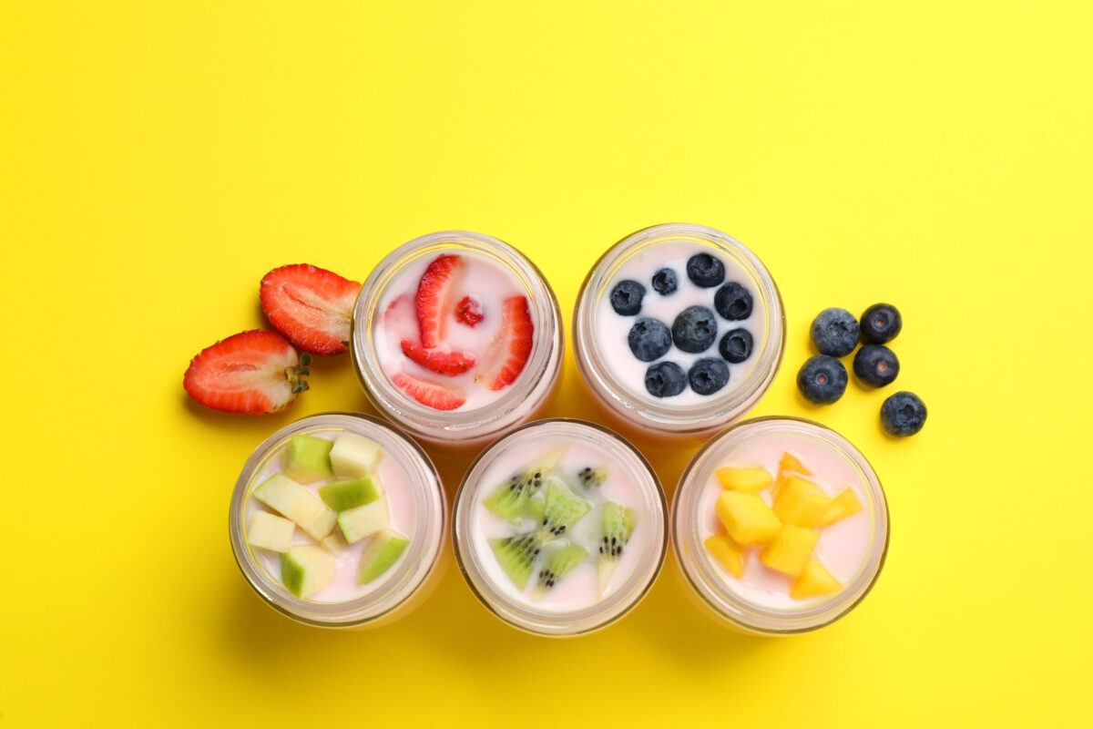 9 Ingredients in Processed Foods That You Should Avoid at All Costs 1 Tasty yogurt in glass jars and ingredients on yellow background, flat lay