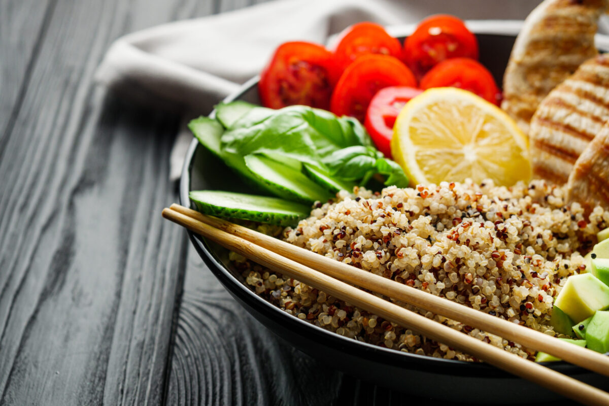 The Truth Behind Overrated Foods 5 quinoa salad with grilled chicken and vegetables on a black wooden rustic background.